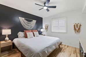 A bedroom with a bed, two bedside tables, a ceiling fan, a window with blinds, and wall decorations. - Cozy Stylish Apt in Omaha`s Medical District! (Omaha)