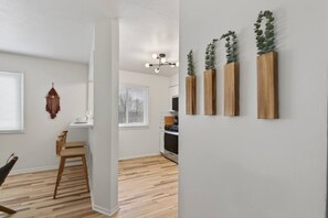 Eine moderne Küche mit weißen Schränken, einem Holztisch und einer Pendelleuchte.