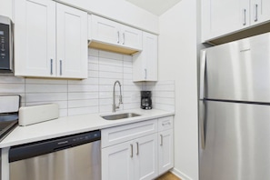 A modern kitchen with white cabinetry, stainless steel appliances, and a dishwasher. - Cozy Stylish Apt in Omaha`s Medical District! (Omaha)