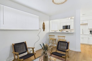 A modern kitchen with white cabinets, a microwave, and a dining area with two wooden chairs and a table. - Cozy Stylish Apt in Omaha`s Medical District! (Omaha)