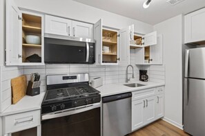 A modern kitchen with white cabinetry, a built-in microwave, a gas stove, and a dishwasher. - Cozy Stylish Apt in Omaha`s Medical District! (Omaha)