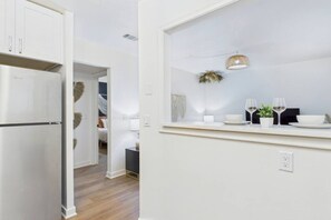 A modern kitchen with white cabinetry, a built-in refrigerator, and a dining area with a table set for two. - Cozy Stylish Apt in Omaha`s Medical District! (Omaha)