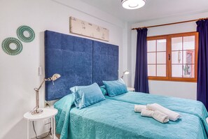 Ein Schlafzimmer mit einem großen Bett, zwei Nachttischen, einem Fenster mit Vorhängen und einer Wand mit dekorativen Tellern.