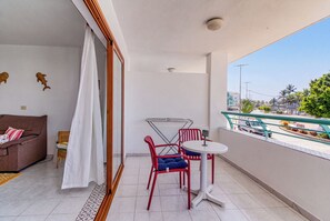 Ein Balkon mit Tisch und Stühlen, einer Couch und Blick auf eine Stadtlandschaft.