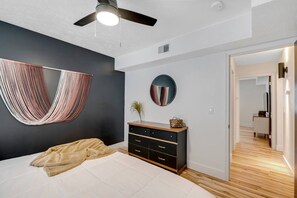 A bedroom with a bed, a dresser, a hanging chair, a mirror, and a ceiling fan. - Prime Location! HGTV Design! (Omaha)