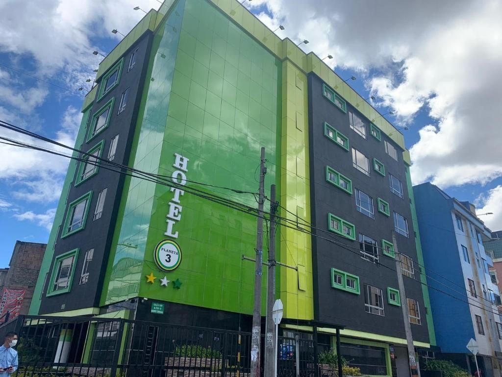 A multi-story hotel with a green facade and a sign indicating it is Planet 3.