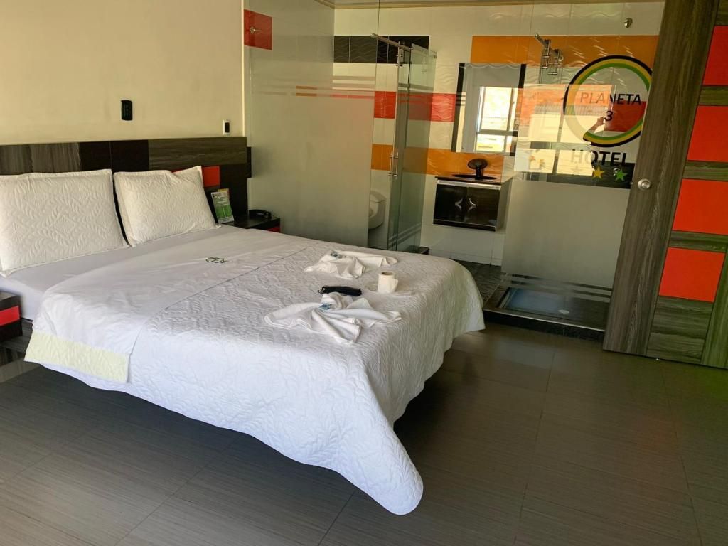Habitación de hotel con cama, mesita de noche, espejo y vista al acceso del hotel.