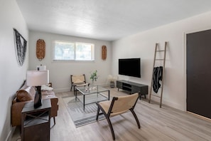 A modern living room with a sofa, coffee table, TV, and a ladder against the wall. - Prime Location! HGTV Design! (Omaha)