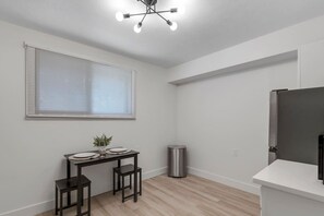 Eine moderne Küche mit einem eingebauten Kühlschrank, einem Esstisch mit Stühlen und einem Fenster mit Jalousien.