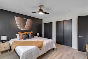 A modern bedroom with a bed, bedside tables, a hanging light fixture, and a ceiling fan. - Prime Location! HGTV Design! (Omaha)