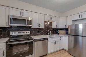 A modern kitchen with white cabinets, stainless steel appliances, and a hexagonal tile backsplash. - Prime Location! HGTV Design! (Omaha)