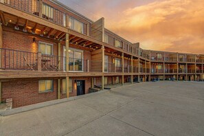 A multi-story motel with a brick facade, balconies, and a parking lot. - Prime Location! HGTV Design! (Omaha)