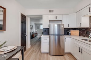 A modern kitchen with white cabinetry, a stainless steel refrigerator, and a wooden countertop. - Prime Location! HGTV Design! (Omaha)