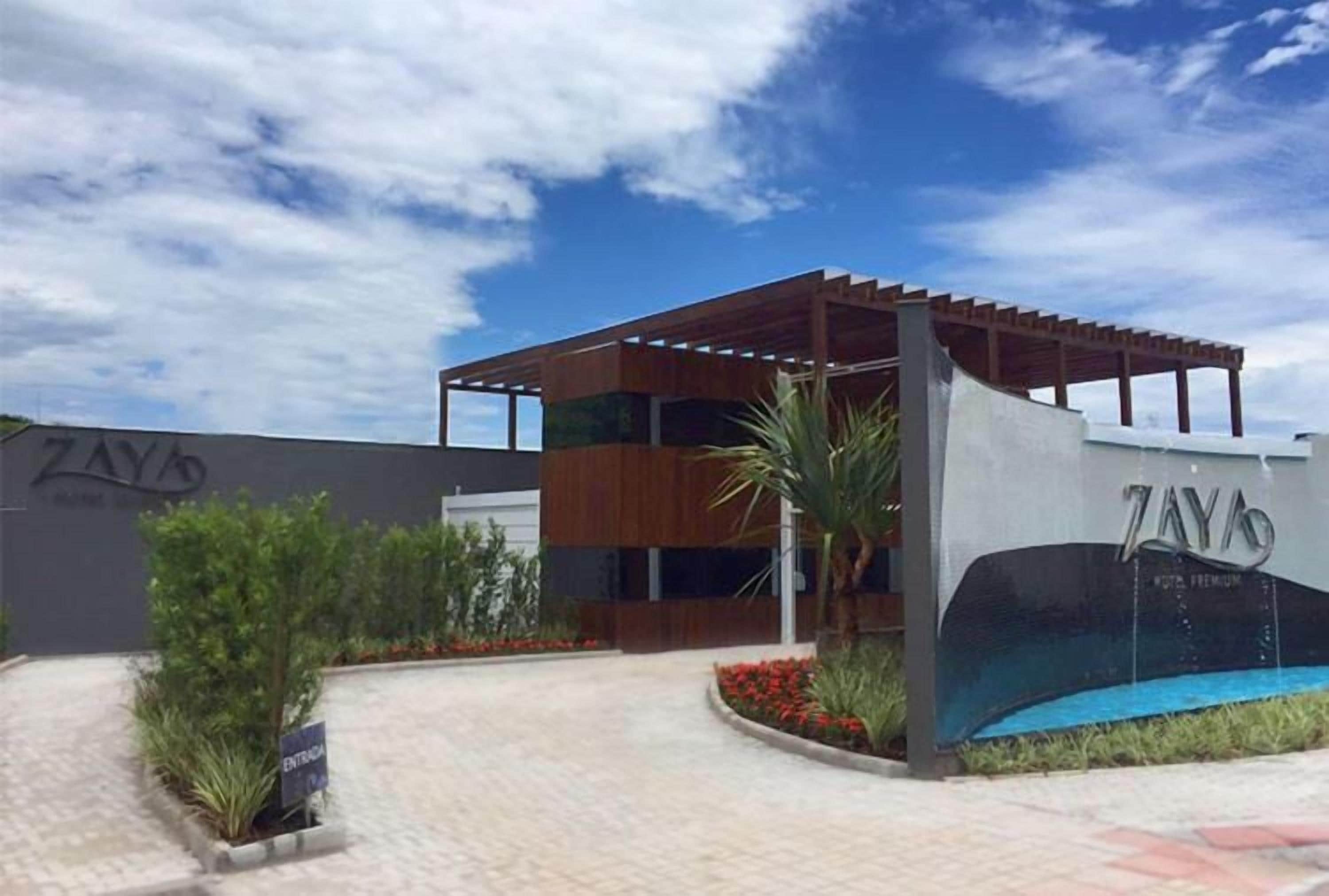 Un edificio moderno con un área exterior techada, piscina y un cartel que dice 'ZAY'S'.