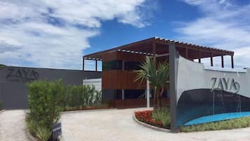 Un edificio moderno con un área exterior techada, piscina y un cartel que dice 'ZAY'S'.