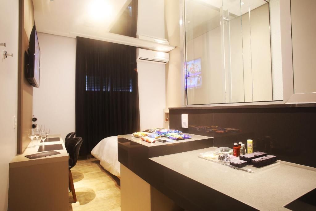 Una habitación de hotel con cama, escritorio, computadora, televisor y minibar.
