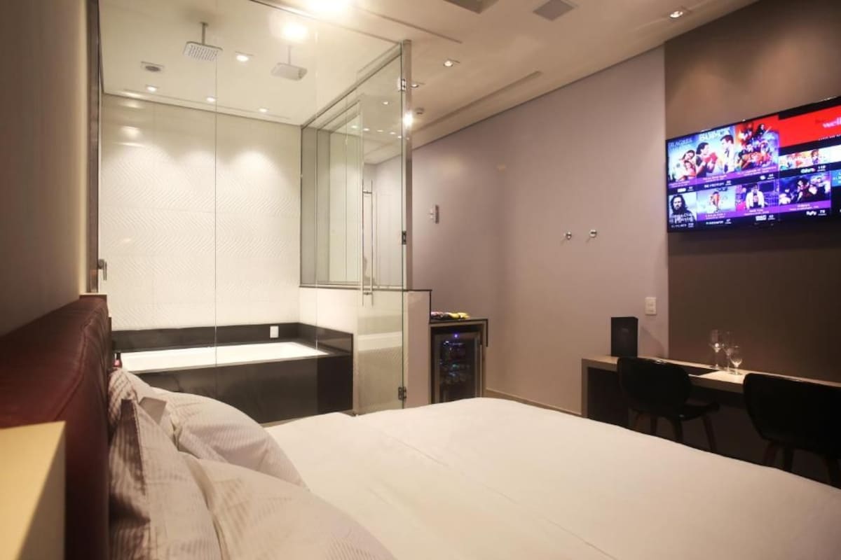 A hotel room with a bed, a desk, a television, and a mirror.