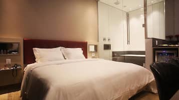 Una habitación de hotel con una cama grande, una mesita de noche con lámpara, un espejo y un armario.