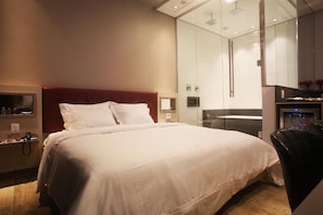 A hotel room with a large bed, a bedside table with a lamp, a mirror, and a wardrobe. - Zaya Motel Premium (Florianópolis)