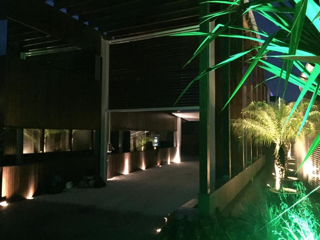 Un edificio moderno con una galería techada y una hilera de palmeras.