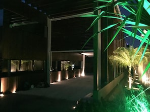 A modern building with a covered walkway and a row of palm trees. - Zaya Motel Premium (Florianópolis)