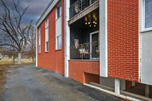 A red brick building with a balcony and a covered entrance. - Designer Mid-Term Living Near Omaha Hospitals (Omaha)