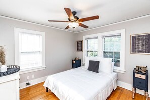 A bedroom with a bed, a ceiling fan, a nightstand, and a window. - Spacious Dundee Duplex | 8BR | Walk to Cafés (Omaha)