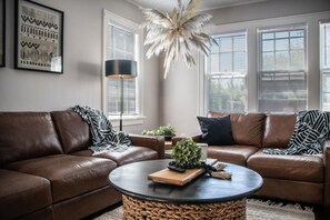 A living room with two brown leather sofas, a round coffee table, and a large potted plant. - Spacious Dundee Duplex | 8BR | Walk to Cafés (Omaha)