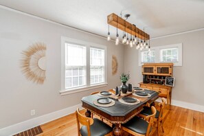 A dining area with a wooden table, black plates, and chairs. - Spacious Dundee Duplex | 8BR | Walk to Cafés (Omaha)