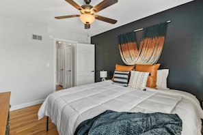 A bedroom with a bed, a ceiling fan, a wall-mounted hammock, and a door leading to another room. - Prime Location Midtown Omaha! (Omaha)