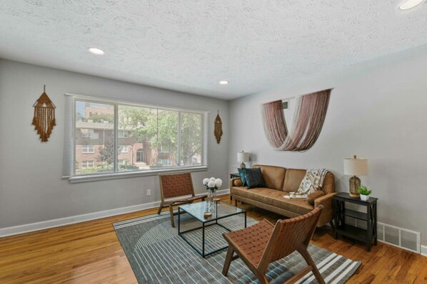 A living room with a sofa, chairs, a coffee table, and a window with blinds. - Prime Location Midtown Omaha! (Omaha)