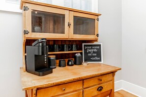 A coffee station with a coffee maker, sugar containers, and a sign. - Storybook Retreat | Walk to Dining & Coffee (Omaha)