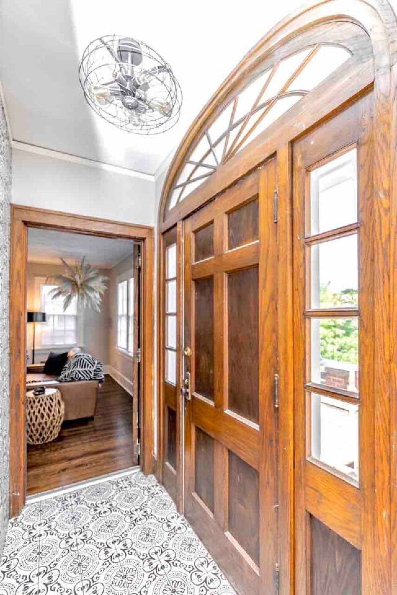 A hallway with wooden doors, a patterned floor, and a seating area with a lamp and cushions.