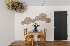 A dining area with a wooden table, four chairs, a vase with flowers, and a black door. - Designer Mid-Term Living Near Omaha Hospitals (Omaha)