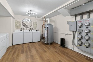 A laundry room with a washing machine, dryer, and a water heater. - Designer Mid-Term Living Near Omaha Hospitals (Omaha)