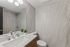 A modern bathroom with a large mirror, two sinks, a toilet, and a shower area. - Designer Mid-Term Living Near Omaha Hospitals (Omaha)