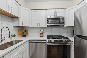 A modern kitchen with white cabinets, stainless steel appliances, and a dishwasher. - Designer Mid-Term Living Near Omaha Hospitals (Omaha)