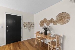 A dining area with a wooden table, chairs, and a vase of flowers. - Designer Mid-Term Living Near Omaha Hospitals (Omaha)