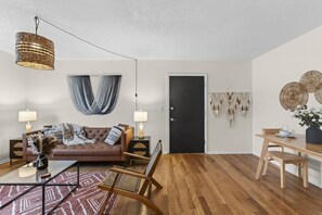 A modern living room with a brown leather sofa, a glass coffee table, and a wooden dining table. - Designer Mid-Term Living Near Omaha Hospitals (Omaha)