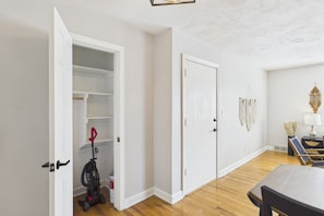 Ein Zimmer mit Holzboden, einem Esstisch, einem Staubsauger und einer geschlossenen Tür.