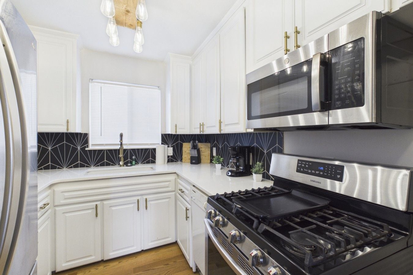 A modern kitchen with white cabinetry, a stainless steel stove, and a microwave.