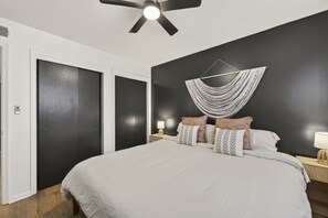 A bedroom with a bed, a ceiling fan, a wall-mounted light, and a door. - Cozy Stylish Apt in Omaha`s Medical District! (Omaha)