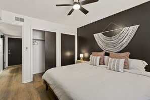 A bedroom with a bed, a ceiling fan, a wall-mounted light, and a door leading to a closet. - Cozy Stylish Apt in Omaha`s Medical District! (Omaha)