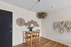 A dining area with a wooden table and chairs, a vase with flowers, and wall decorations including circular woven items and macrame. - Designer Mid-Term Living Near Omaha Hospitals (Omaha)