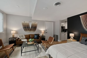 A modern hotel room with a bed, seating area, and a kitchenette. - Prime Location Midtown Omaha (Omaha)