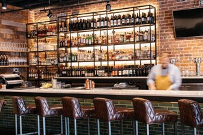 A bar with multiple shelves of bottles, a coffee machine, and leather bar stools. - Prime Location Midtown Omaha (Omaha)