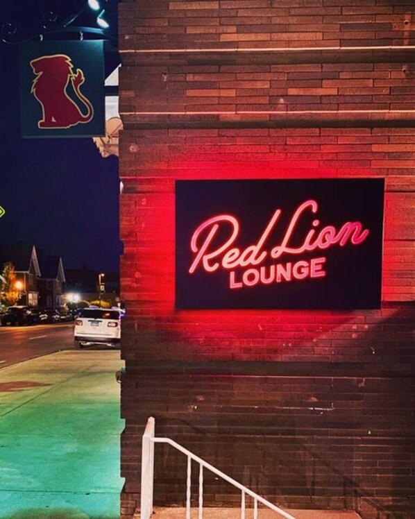 Edificio de ladrillo con un letrero de neón que dice 'Red Lion Lounge' sobre un muro de ladrillo.