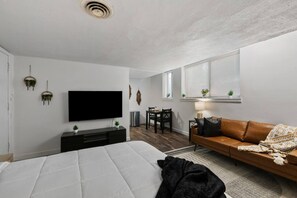 Une chambre moderne avec un grand lit, une télévision, un canapé et un coin repas.