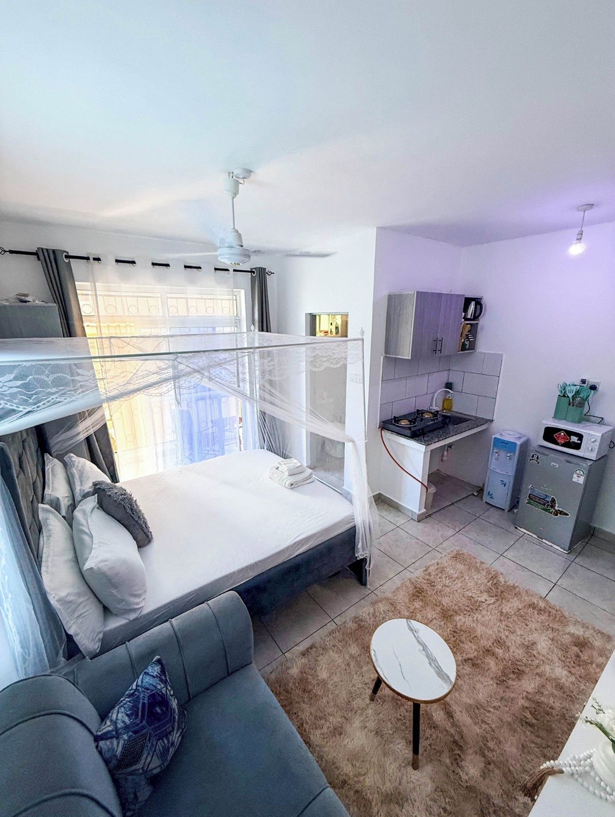 A compact room with a bunk bed, a sofa, a small kitchen area, and a dining table.