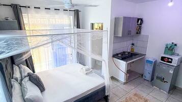 A compact room with a bunk bed, a sofa, a small kitchen area, and a dining table.
